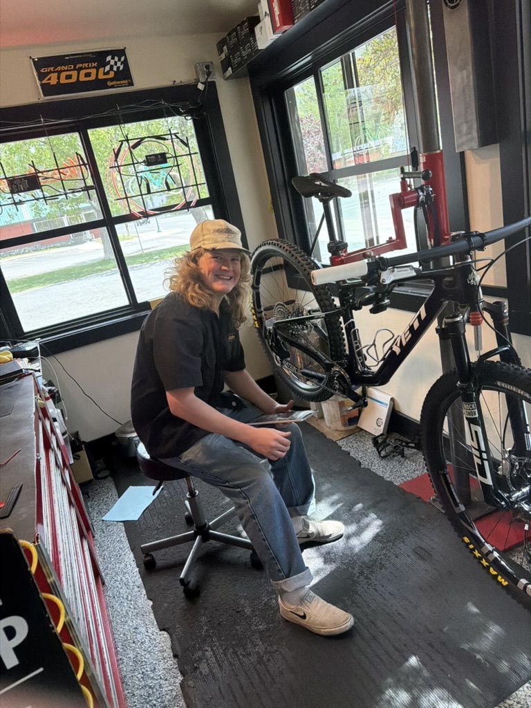 Power House bike technician smiling beside a mountain bike in the service area